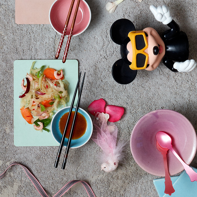 Table with Asian dishes on colorful plates.