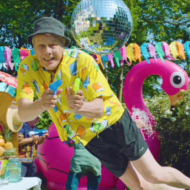 Man jumping in pool, big pink flamingo in the background.