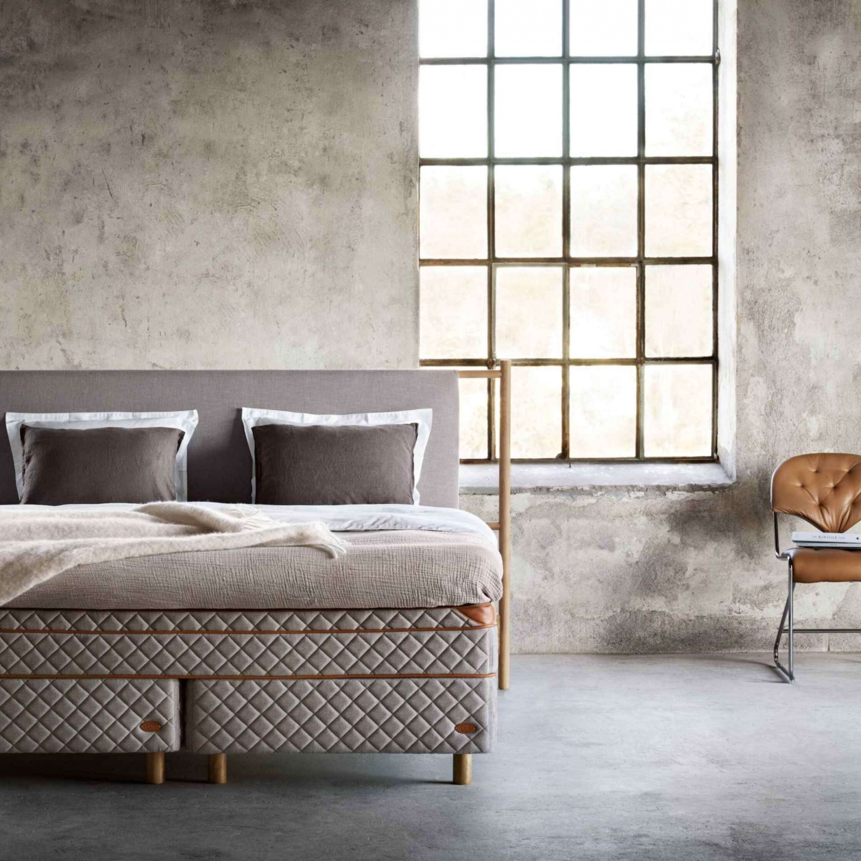 Bed and chair in front of a window.