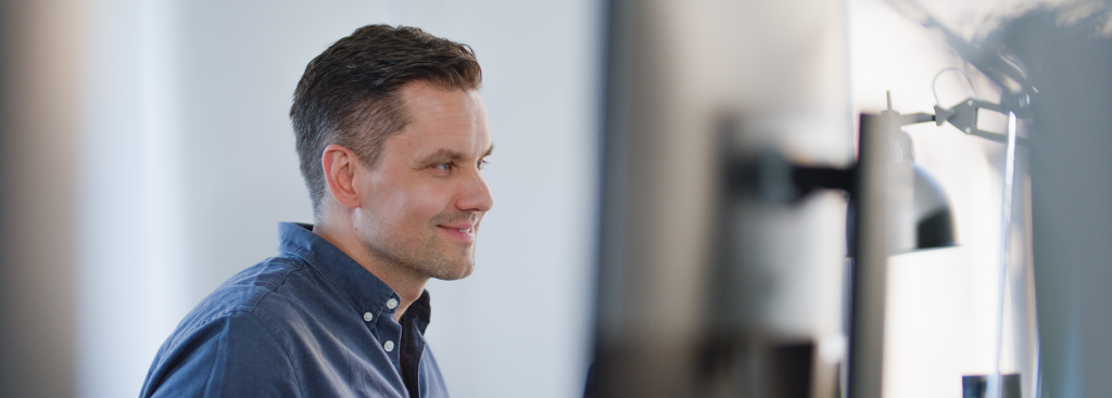 a man smiling while working on his computer