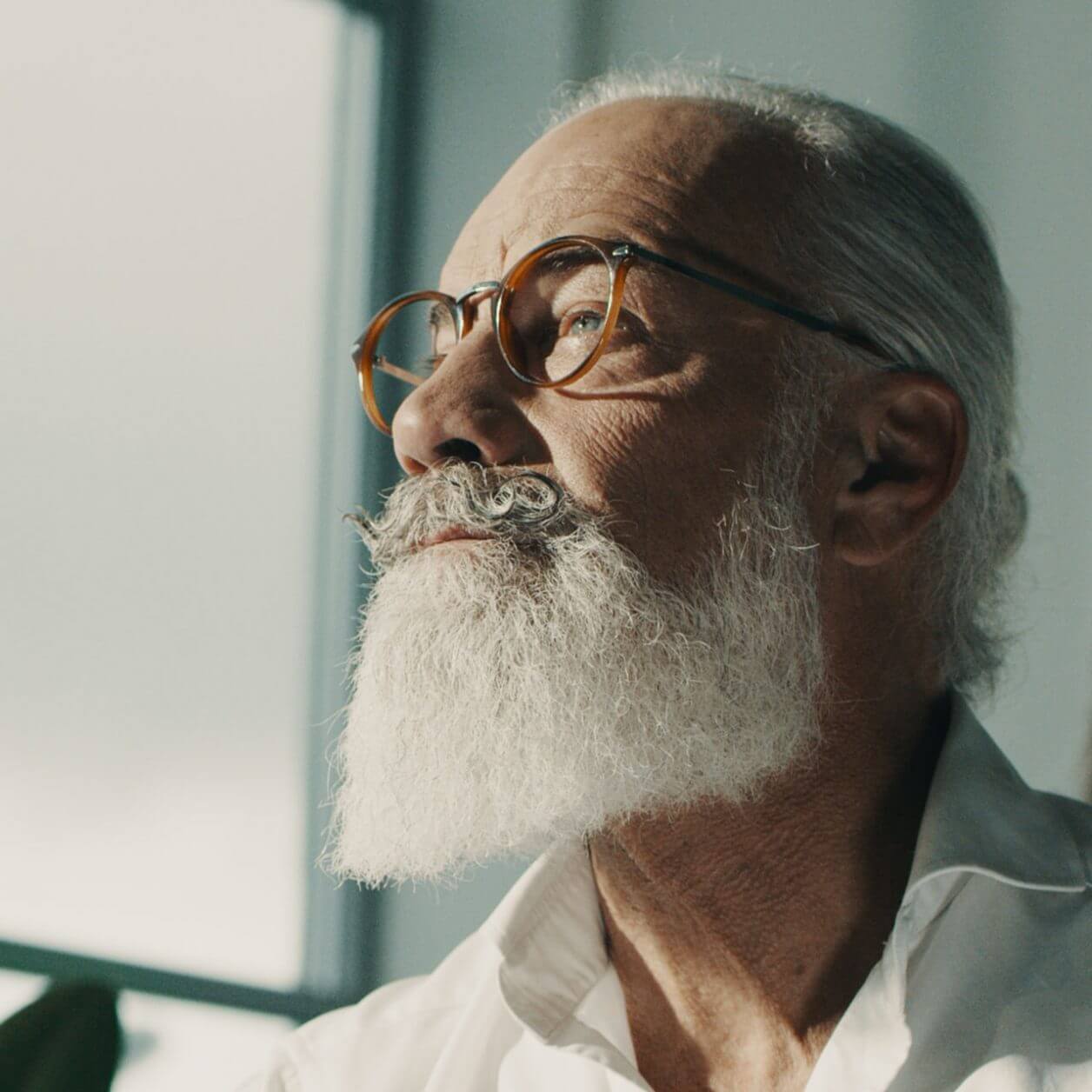 Solbränd man med skägg sitter i ateljé.