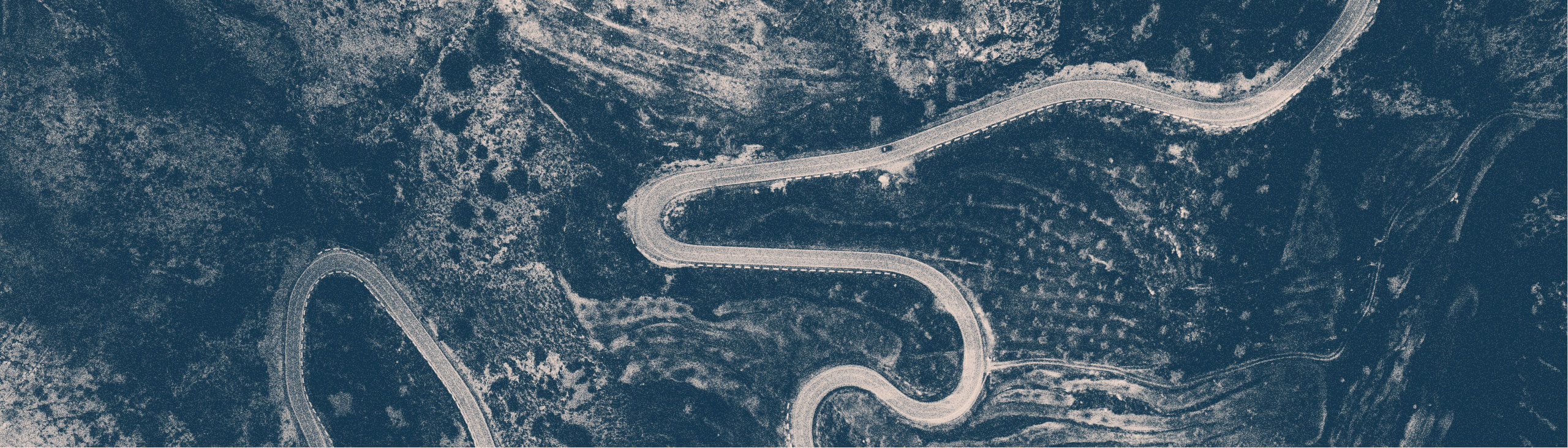 Serpentinväg i bergen fotograferad ovanifrån.