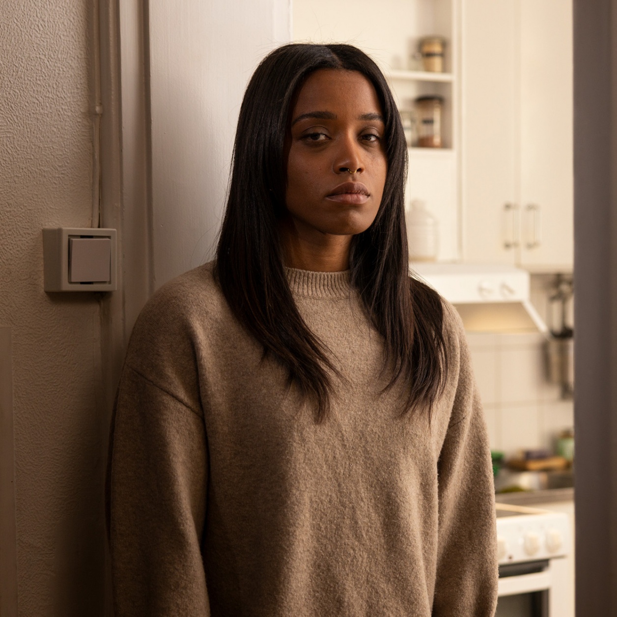 Flicka i beige tröja som ser ledsen ut.